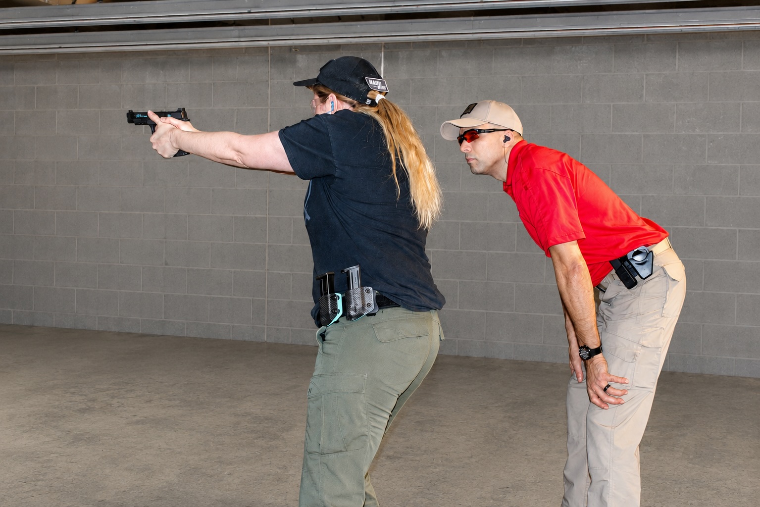 Woman using firearm in gun range under supervision of instructor
